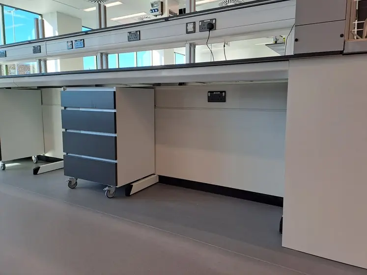 Laboratory workbench with mobile under-counter cabinets and an overhead service spine